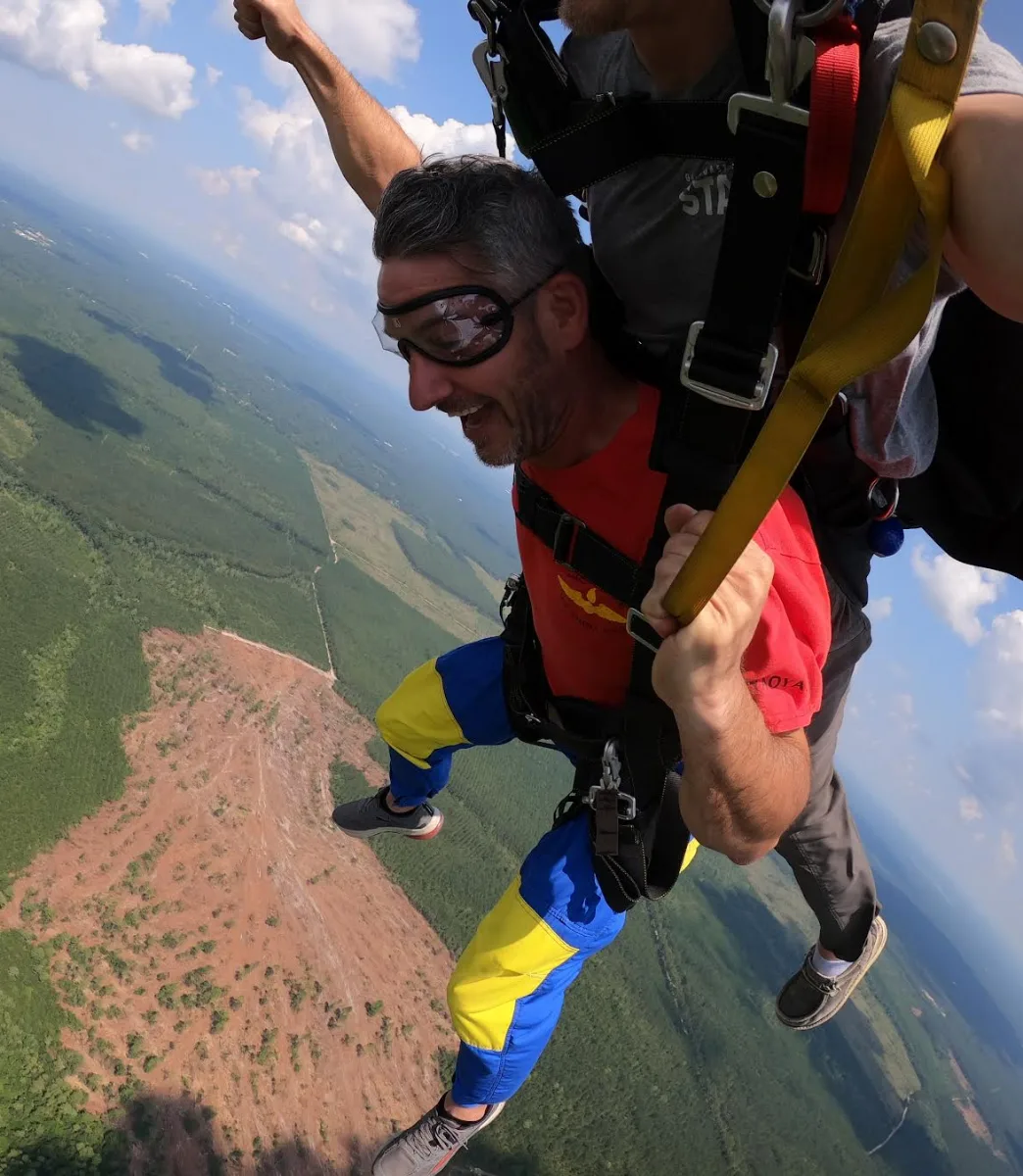 Tandem skydivers in freefall above the Gulf Coast landscape